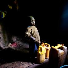 A young Burundi child stands in his home